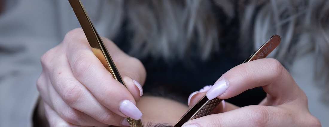 Gouden pincetten tijdens het zetten van wimperextensions
